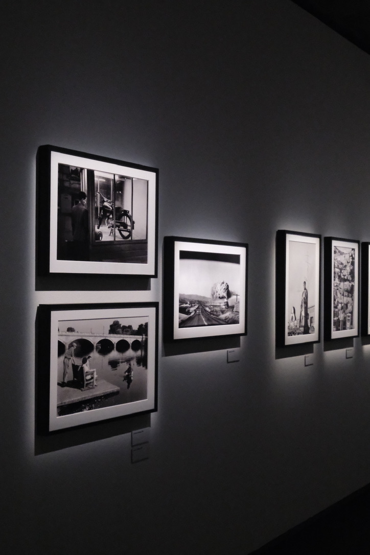 Gallery wall of framed black-and-white photographs in spotlit exhibition space