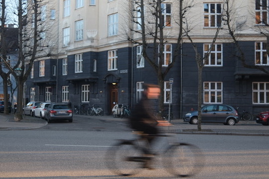 Motion-blurred cyclist on a European street beside classic apartment architecture