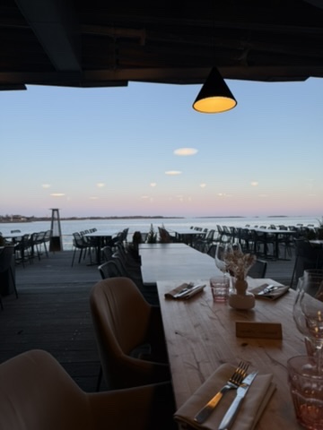 Waterfront restaurant patio at dusk, set table and calm water