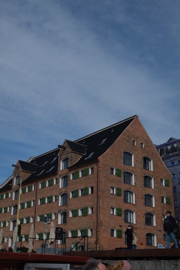 Historic red-brick gabled building on the waterfront, low angle from the water